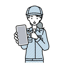 立ってスマートフォンを指差してこちらに向けて見せている作業員の女性