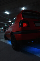 Fototapeta na wymiar Classic beautiful tuned red car in the parking lot at night