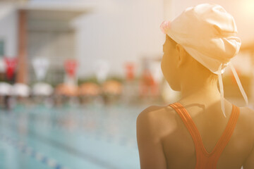 An orange light streaked across the young female athletes standing with their backs ready for the swimming competition.