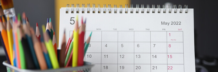 Calendar for May with colored pencils is on table