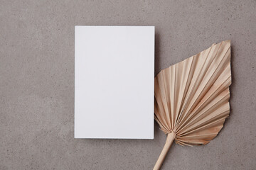 Blank invitation card for a natural wedding or celebration event with dried palm leaf stem