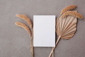 Bohemian blank invitation card surrounded by natural dried palm leaf and grasses. Wedding and celebration background
