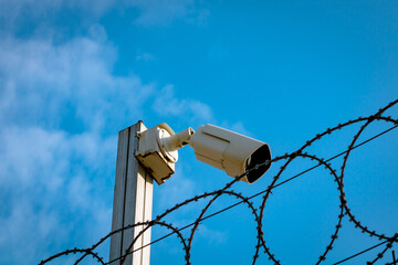 A security camera or CCTV camera with barbed wire fence. Security background.