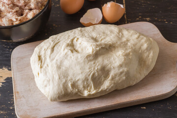 Raw unleavened dough for dumplings on a wooden table