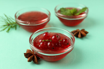 Bowls with cranberry sauce on mint background
