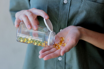 woman pours out of a jar pills with cod liver oil