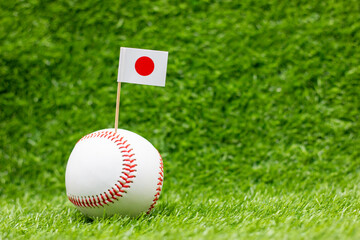 Baseball with flag of Japan is on green grass