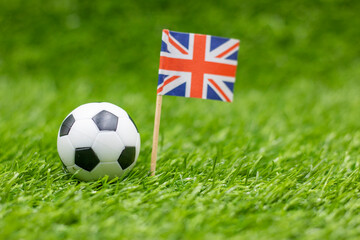 Soccer ball with Union Jack flag on green grass