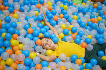 Fototapeta na wymiar boy playing in playground colourful ball pool. Happiness in bright colors.