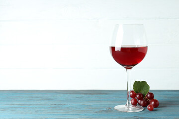 Glass of red wine and grape on wooden table