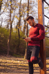 Man chatting online using smart phone while taking a workout break
