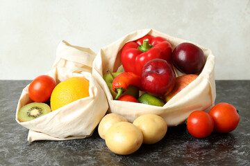 Bags with vegetables and fruits on black smokey table