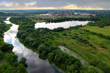 Fototapeta na wymiar Aerial view of the river against the background of cloudy clouds in rainy weather. Wetlands near the countryside. Soft focus.