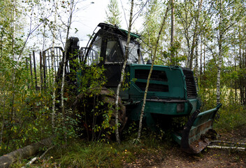 Fototapeta na wymiar Crane forwarder machine during clearing of forested land. Wheeled harvester transports raw timber from felling site out. Harvesters, Forest Logging machines. Forestry forwarder on deforestation.