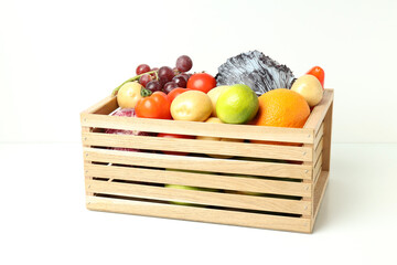 Wooden box with vegetables and fruits on white table