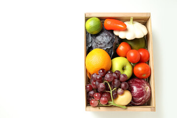 Wooden box with vegetables and fruits on white background