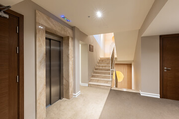 Interior of a carpeted hotel corridor with stainless steel lift door