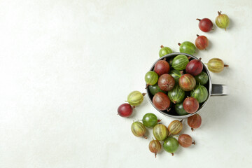 Cup of ripe gooseberry on white textured background
