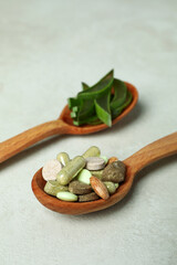 Concept of herb pills with aloe slices on white textured background