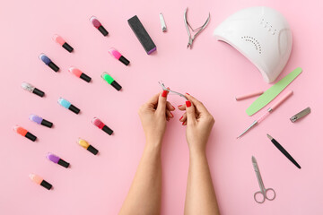 Female hands with manicure cutter and tools on color background