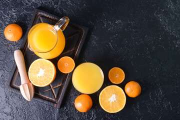 Glass and jug with tasty citrus juice on dark background