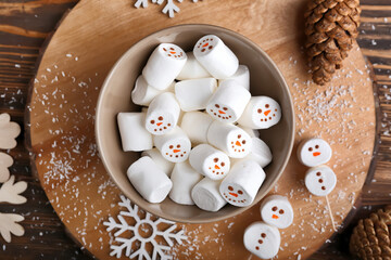 Bowl with snowmen made of soft marshmallows on wooden background