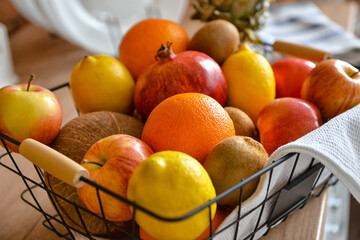 Basket with tropical fruits on counter in kitchen, closeup