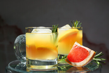Fototapeta premium Glasses of tasty grapefruit cocktail with rosemary on black background