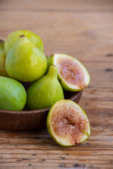 Close-up of wooden plate with figs, one open, selective focus, on wooden table, vertical, with copy space
