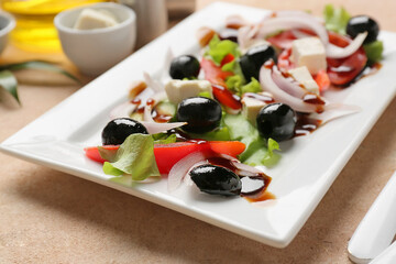 Plate of fresh Greek salad on light background, closeup