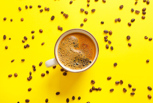 Cup of coffee and scattered beans on color background © Pixel-Shot