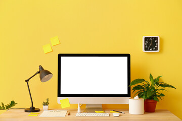 Modern workplace with computer and decor near color wall