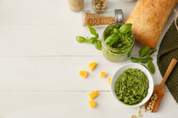 Bowl with tasty pesto sauce, cheese and pine nuts on light wooden background