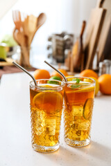 Glasses of tasty ice tea with lemon on table in kitchen