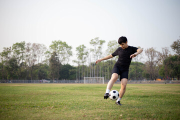 Sports and recreation concept a male soccer player wearing black t-shirt and pants practicing...