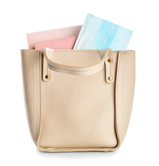 Female handbag with notebooks and medical mask on white background