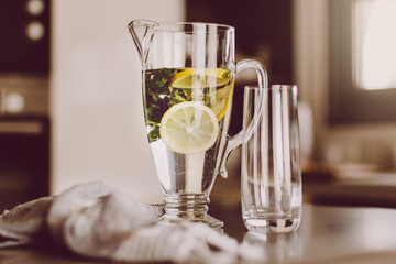 Transparent jug with summer fresh limonade. Cozy home kitchen interior details.