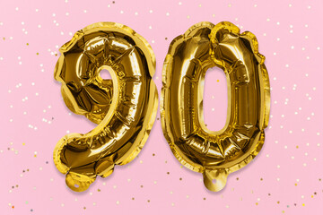 The number of the balloon made of golden foil, the number ninety on a pink background with sequins....