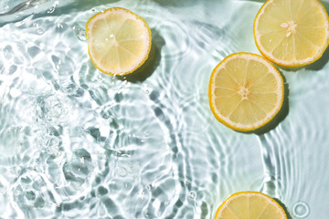 Fresh pieces of lemon and clean blue water,bright sunlight.Empty space.Lemons and splashing water...