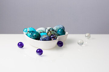 Easter blue quail eggs in a plate in the shape of a heart on a white table