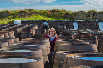Young scotish woman between whiskey barrels and casks in Islay Scotland