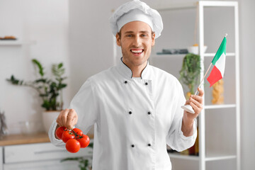 Handsome chef with Italian flag and fresh tomatoes in kitchen
