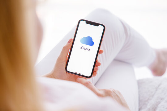 Riga, Latvia - March 26, 2021: Woman holding mobile phone with iCloud logo on the screen