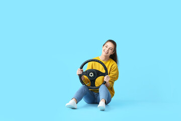 Fototapeta na wymiar Young woman with steering wheel on color background
