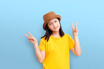 Obraz na płótnie Canvas Portrait of Asian teenage cute girl wear a brown hat and showing v-sign finger isolated over blue pastel background.