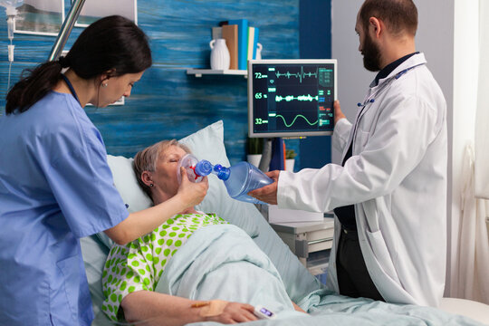 Social support asisstants helping sick hospitalized senior woman breath, with ambu bag during resustacitor process. Social services nursing elderly retired female. Healthcare assistance