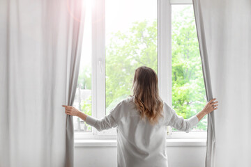 Woman opening light curtains in modern room