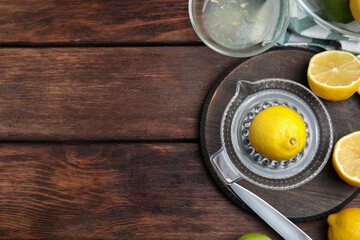 Glass squeezer and fresh lemons on wooden table, flat lay. Space for text