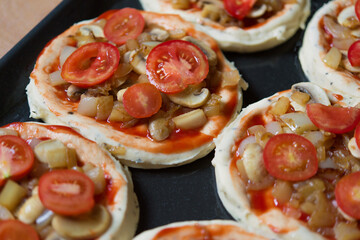 Mini pizza. Six pieces of pizza before baking. Baking tray with blanks, before placing in the oven.	