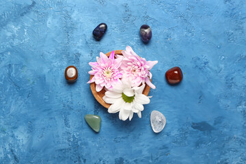 Bowl with flowers and set of chakra stones on color background